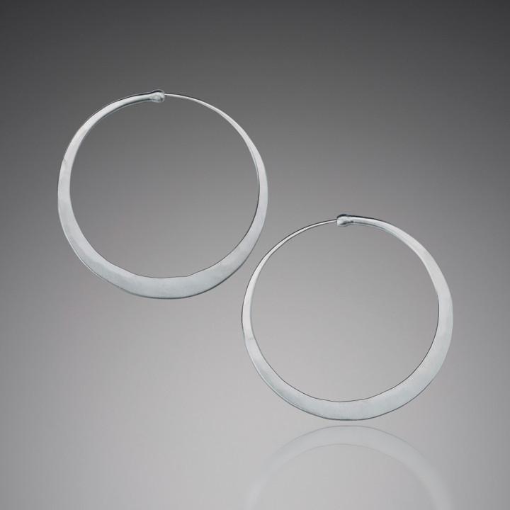 Matte sterling silver hoop earrings by Mostly Sweet Jewelry. Features minimalist design with smooth, non-reflective finish against gray background. Simple elegant circular shape with subtle handcrafted quality. Perfect for everyday wear with hypoallergenic sterling silver construction.